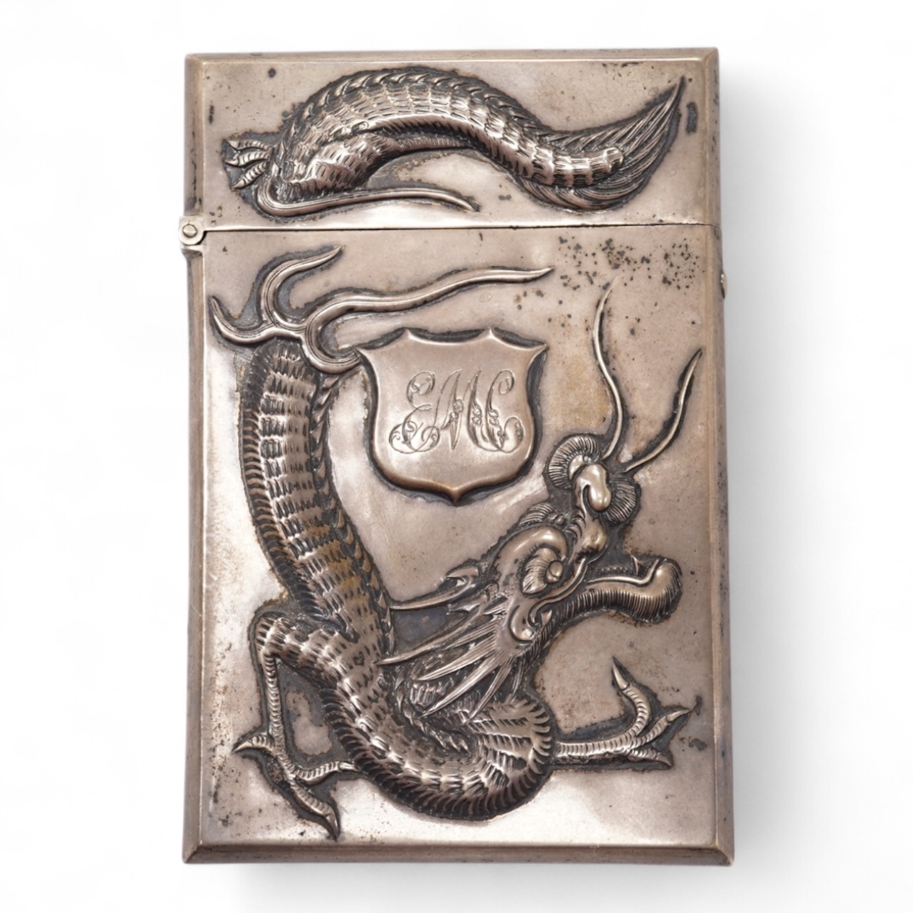 A late 19th century Chinese Export white metal card case, by Cum Shing, Canton, embossed with a dragon and applied shield shaped panel engraved with monogram, 90mm, 85 grams.
